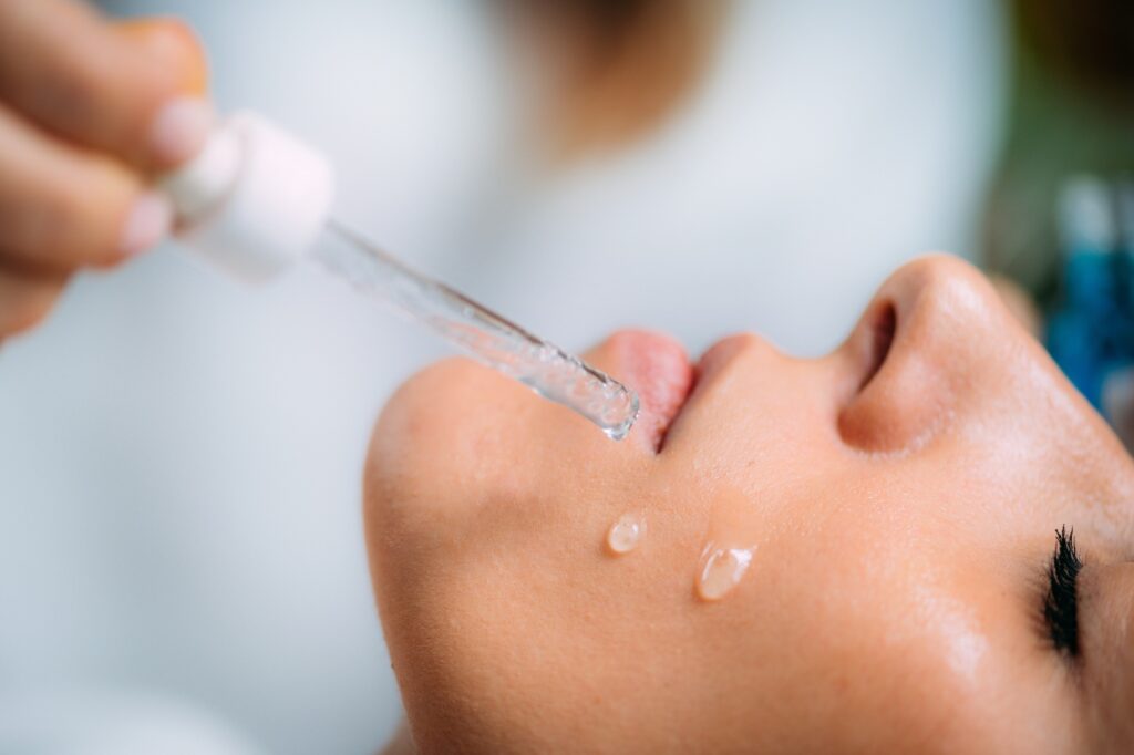 Cosmetician Applying Hyaluronic Acid Serum on Woman’s Face