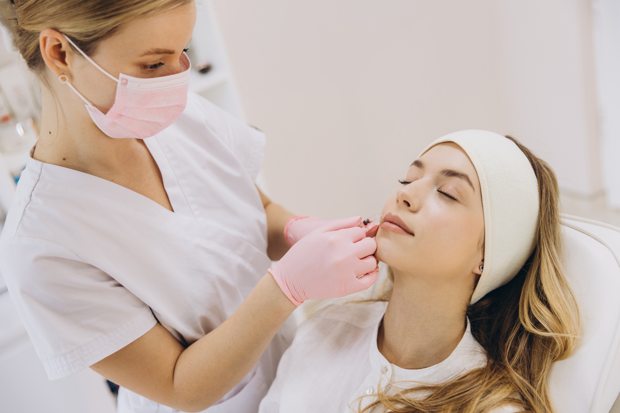 Cosmetologist performing a botox injection in a woman's lips at a modern aesthetic medicine clinic