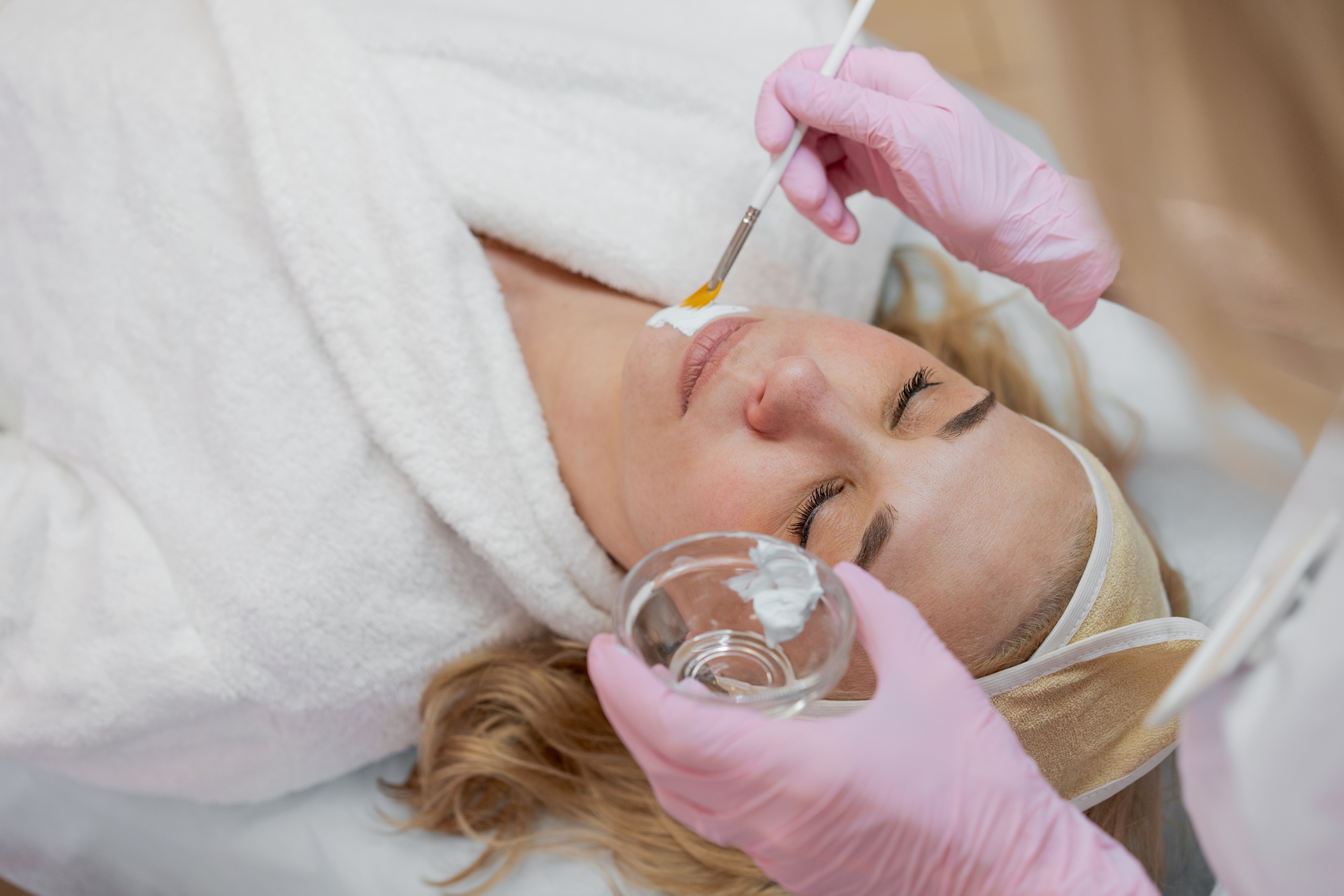 Female cosmetologist makes facial procedures for client clinic in aesthetic