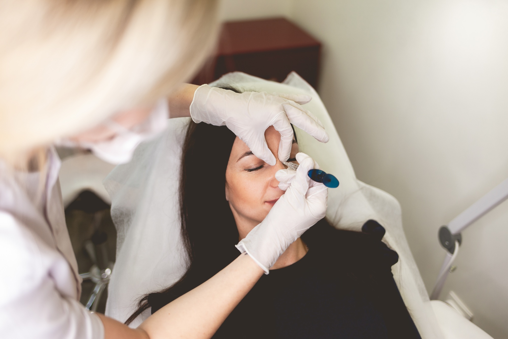 Woman make injection of beauty in the nose. Botox procedure in beauty salon